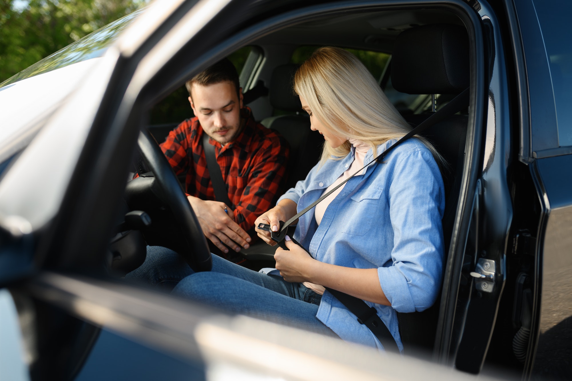 Fahrschülerin schnallt sich an, während der Fahrlehrer Anweisungen gibt – Fahrschule-Peak Fahrtraining.